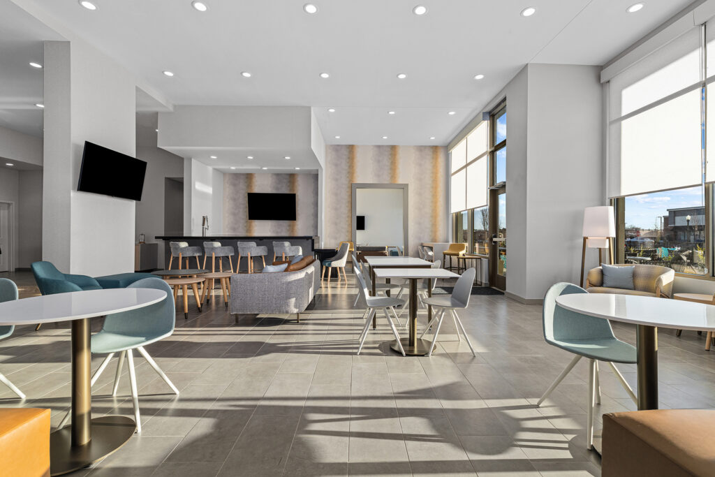 A modern, spacious lounge area at TownePlace Suites Murfreesboro features large windows, cozy sofas, flat-screen TVs, and neutral décor. Natural light streams in, creating a bright, welcoming atmosphere that embodies true hospitality.